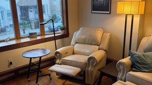 A living room with a large window, a leather armchair, a sofa, a small table, and a floor lamp. - Huge 1BR with central AC+laundry in quiet area MINUTES from Ridgewood & Bushwick (New York)