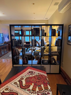 Una habitación con una estantería, un televisor y una alfombra estampada.