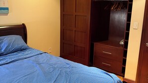 A bedroom with a bed, a wooden wardrobe, and a closet with hanging space. - Huge 1BR with central AC+laundry in quiet area MINUTES from Ridgewood & Bushwick (New York)