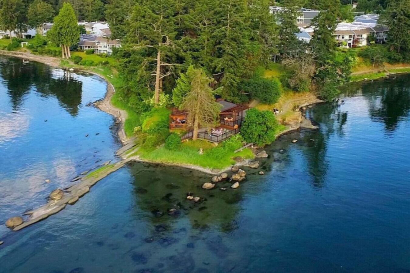 A lakeside property with a wooden dock, a gazebo, and a house surrounded by dense trees.