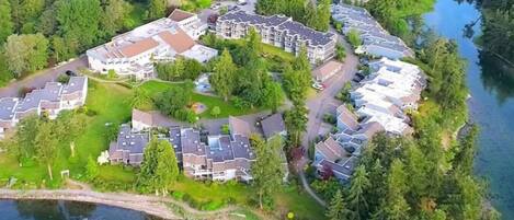 Um bairro residencial com várias casas de dois andares, um lago pequeno e uma floresta densa ao redor da comunidade.