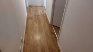A narrow hallway with wooden flooring and white walls. - Citylink 2-bedroom flat, 8 mins to London bridge. Sleeps 7. (London)