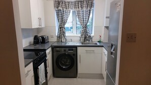 A compact kitchen with a washing machine, a dishwasher, a coffee maker, and a toaster. - Citylink 2-bedroom flat, 8 mins to London bridge. Sleeps 7. (London)