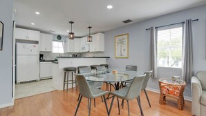A modern kitchen with white cabinets, a central island, and a dining area with a glass table and chairs. - Casa Havana | Old Town Condo w/ Pool & Balcony (Key West)