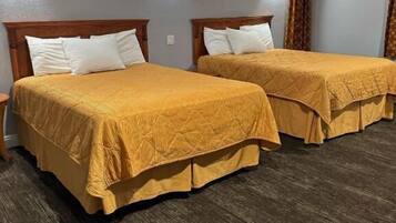 Quarto de hotel com duas camas, cabeceiras de madeira e chão de madeira escura.