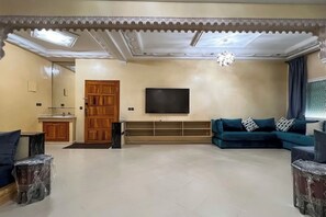 Een woonkamer met een televisie, een bank en een houten kast.