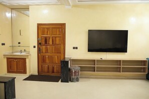 Een woonkamer met een houten deur, een aan de muur bevestigde televisie, een houten kast en een marmeren accent.