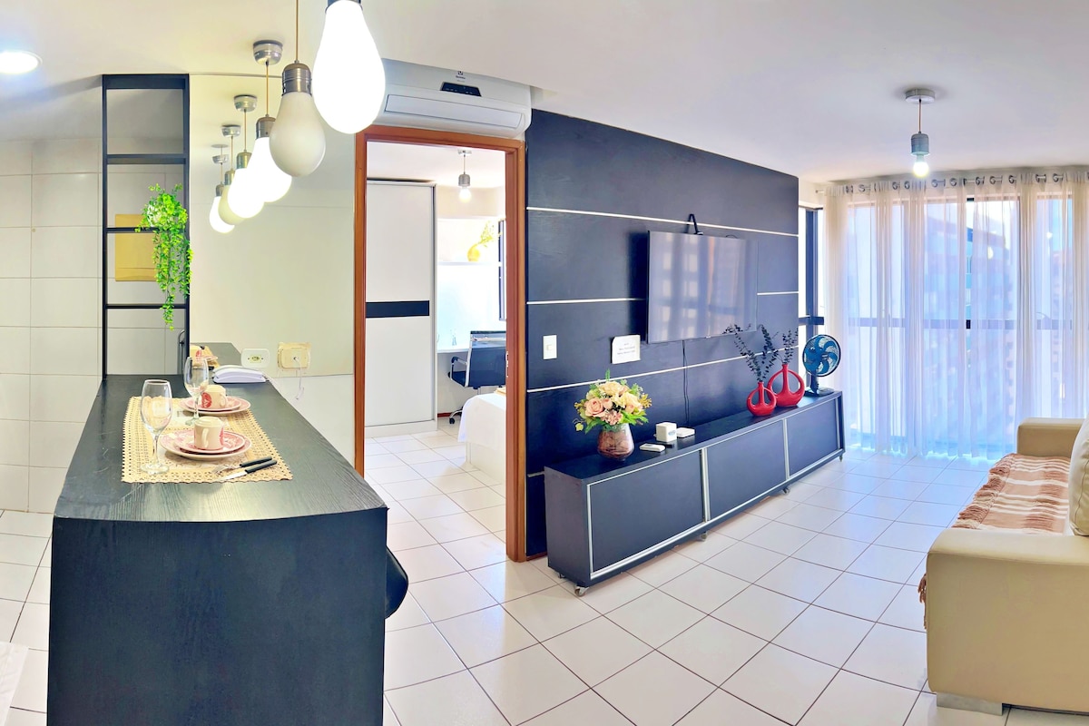 A modern living room with a black entertainment unit, a beige sofa, and a dining area with a table set for two.