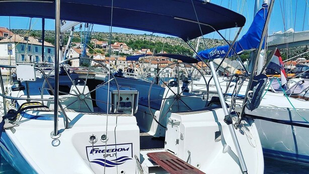 Un barco amarrado en un puerto deportivo con una cubierta techada, un timón y un logotipo que dice "Freedom Split".