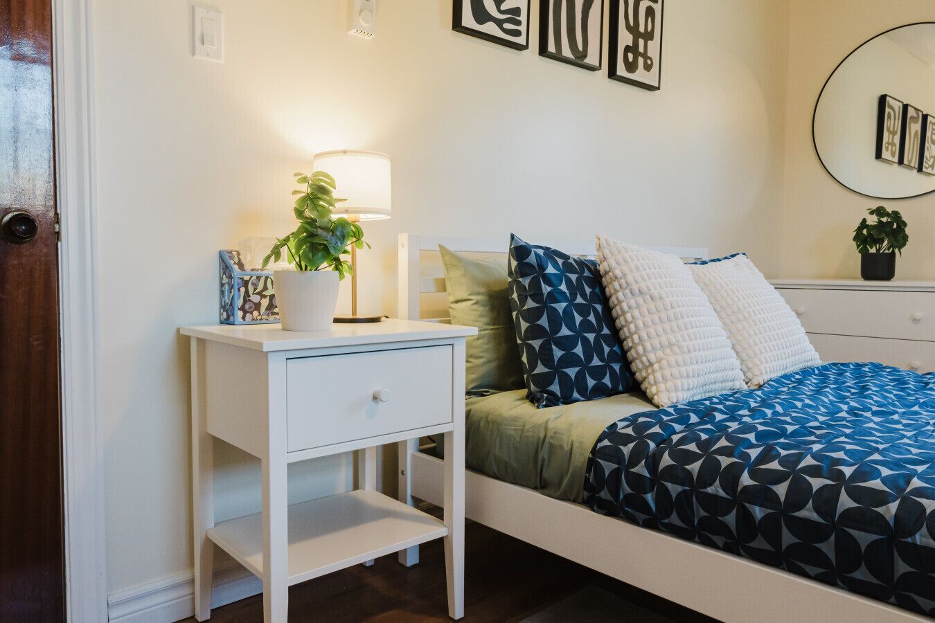 Un dormitorio con cama, mesita de noche, lámpara y decoración en la pared.