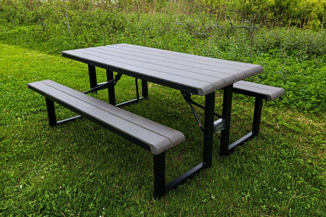 Una mesa de picnic con bancos en un espacio al aire libre cubierto de césped.