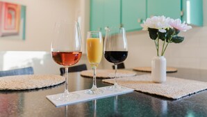 Three glasses of beverages on a kitchen counter with a woven placemat, a white vase with flowers, and teal cabinets in the background. - Sydney Retreat | 3BR, 2 Bath Home with Deck & BBQ (Sydney)