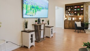 A living room with a flat-screen TV, wooden cabinets, a bookshelf, and a chair. - Sydney Retreat | 3BR, 2 Bath Home with Deck & BBQ (Sydney)