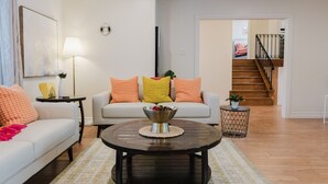 A living room with a sofa, a coffee table, and a staircase leading to an upper floor. - Sydney Retreat | 3BR, 2 Bath Home with Deck & BBQ (Sydney)