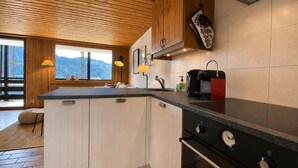 Une cuisine avec un plafond en bois, une grande fenêtre et un four encastré.