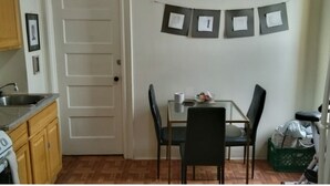Pieni ruokailutila, jossa on pöytä ja tuolit, valkoinen ovi ja seinä, jossa on kehystettyjä kuvia.