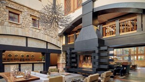Eine geräumige Lobby mit einer Steinwand, einem Kamin und gemütlichen Sitzbereichen.