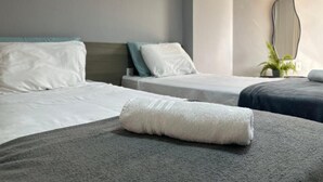 A hotel room with two beds, each with white linens and a grey blanket. There is a potted plant on the right side of the room. - Flat 127-GF na Praia de Cabo Branco (João Pessoa)
