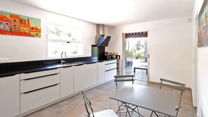 A modern kitchen with white cabinets, a black countertop, and a window overlooking a garden. - Villa for 15 people - Private pool - Air conditioning - WiFi - Sainte Maxime - 5-star rated (STE MAXIME)