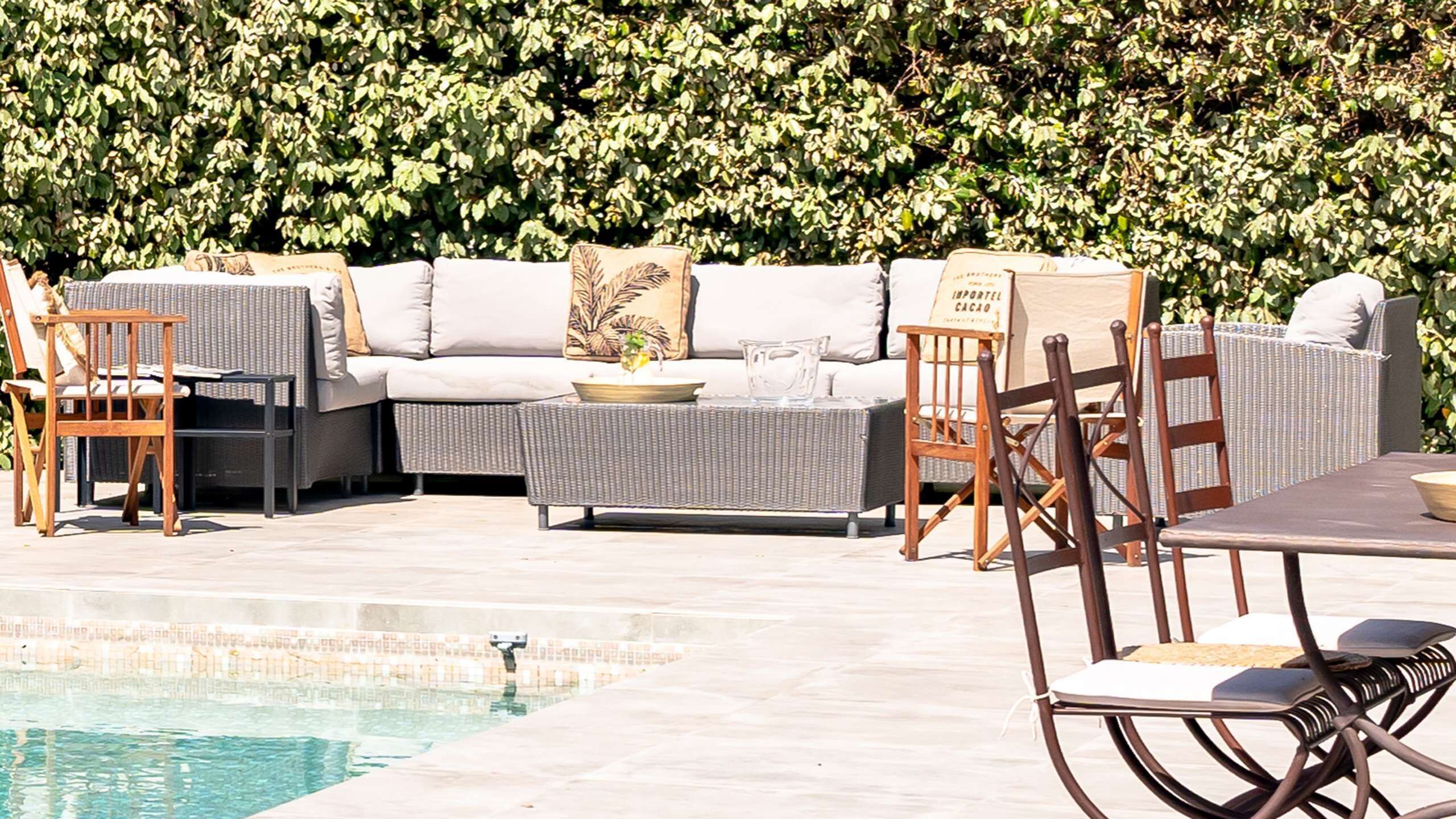 Un área junto a la piscina con sofás, sillas y una mesa.