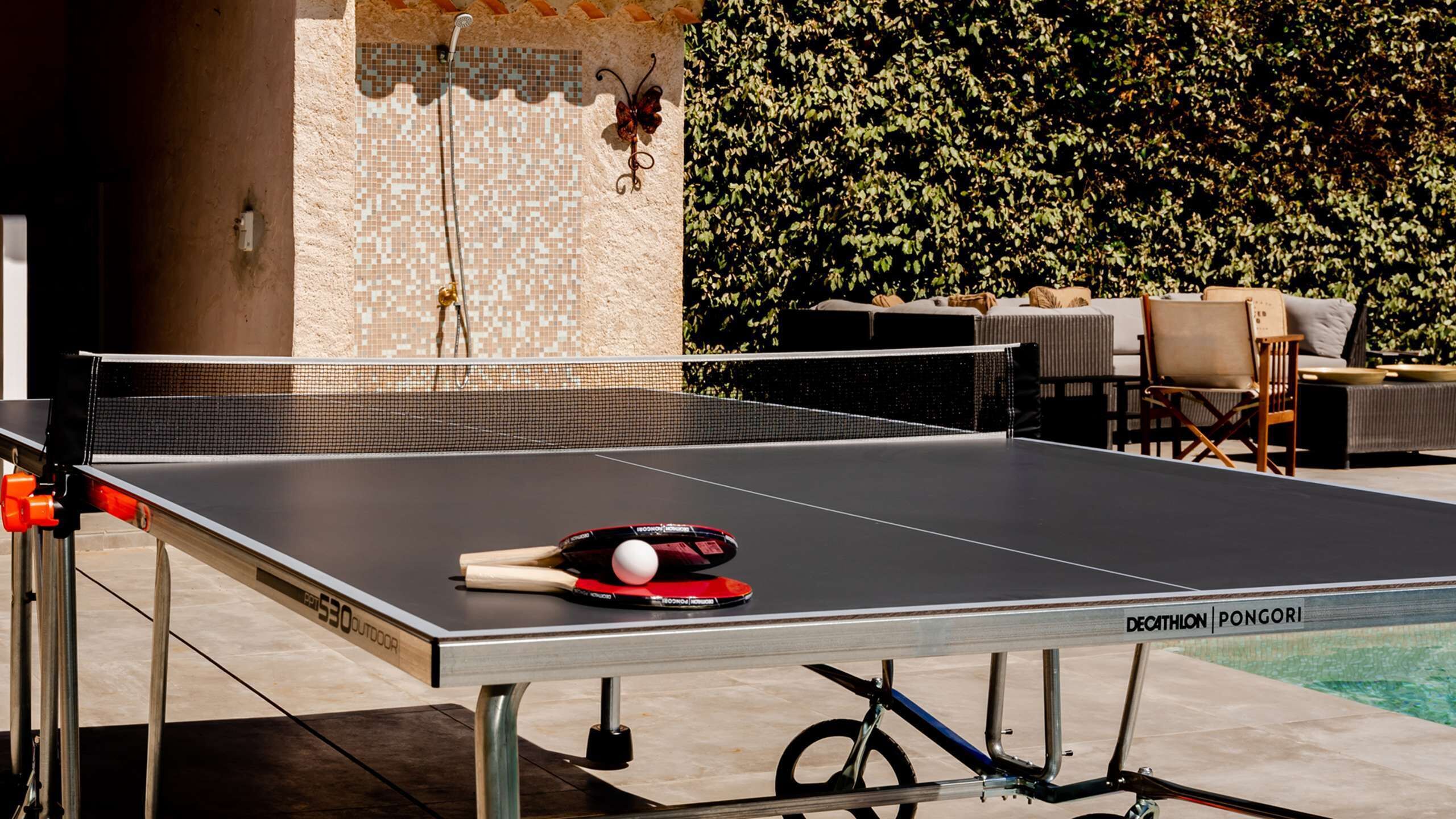 A ping pong table with a net, a paddle, and a ball.