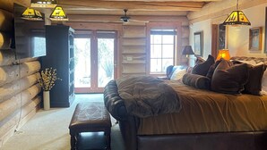A log cabin bedroom with a bed, bench, and hanging lamps.