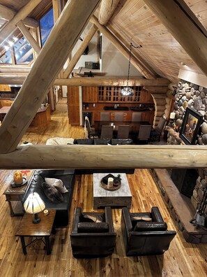 A log cabin interior with a dining area, kitchen, and a stone wall. - Moose Hollow Rustic Log Cabin Rustic Weber River Retreat in Oakley, UT Sleeps 22 (Oakley)