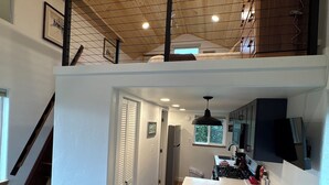 Une cuisine spacieuse dotée d’un îlot central, de planchers en bois et d’une chambre à coucher située en mezzanine.