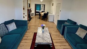 Uma sala de estar com dois sofás verde-água, uma mesa de centro de mármore e um tapete vermelho.