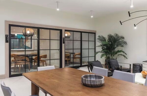 A modern dining area with a wooden table, chairs, and a large potted plant. - King Deluxe Studio (Miami)