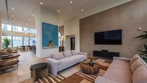 A spacious living area with a large sofa, a coffee table, and a flat-screen TV mounted on the wall. - King Deluxe Studio (Miami)
