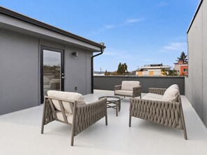 Eine Dachterrasse mit Korbmöbeln und einer Glastür.
