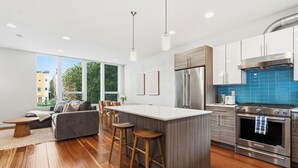 A modern kitchen with a central island, stainless steel appliances, and a view of the city. - Rooftop Retreat w/ Stunning Views | Ballard Gem (Seattle)
