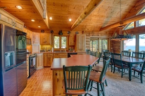 A cabin interior with a kitchen, dining area, and large windows overlooking a natural landscape.