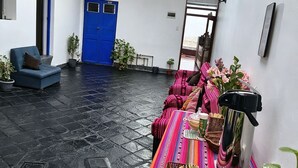 A courtyard with a blue door, a blue bench, and a table with colorful textiles and plants. - Hostal Flor de Loto  (Cusco)
