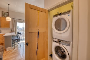 A laundry room with a washing machine and dryer, wooden door, and a small kitchenette area with a dining table and chairs.