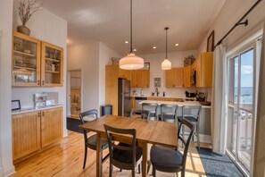 A modern kitchen with wooden cabinets, a dining table with chairs, and pendant lighting. - Downtown Bayfield Lodging in Historic Building (Bayfield)