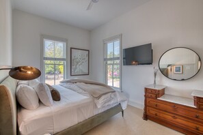 Une chambre à coucher avec un lit, une commode, un téléviseur et une fenêtre.