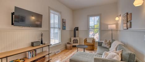 Un salon avec un téléviseur, un canapé, un fauteuil et une petite table.