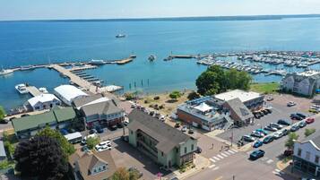 A marina with boats docked, a parking area, and buildings with commercial establishments.