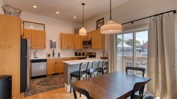 A modern kitchen with wooden cabinets, a central island, and pendant lighting.