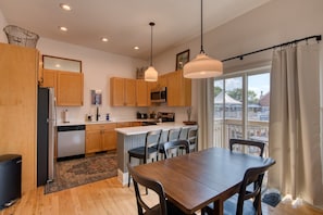 A modern kitchen with wooden cabinets, a central island, and pendant lighting.