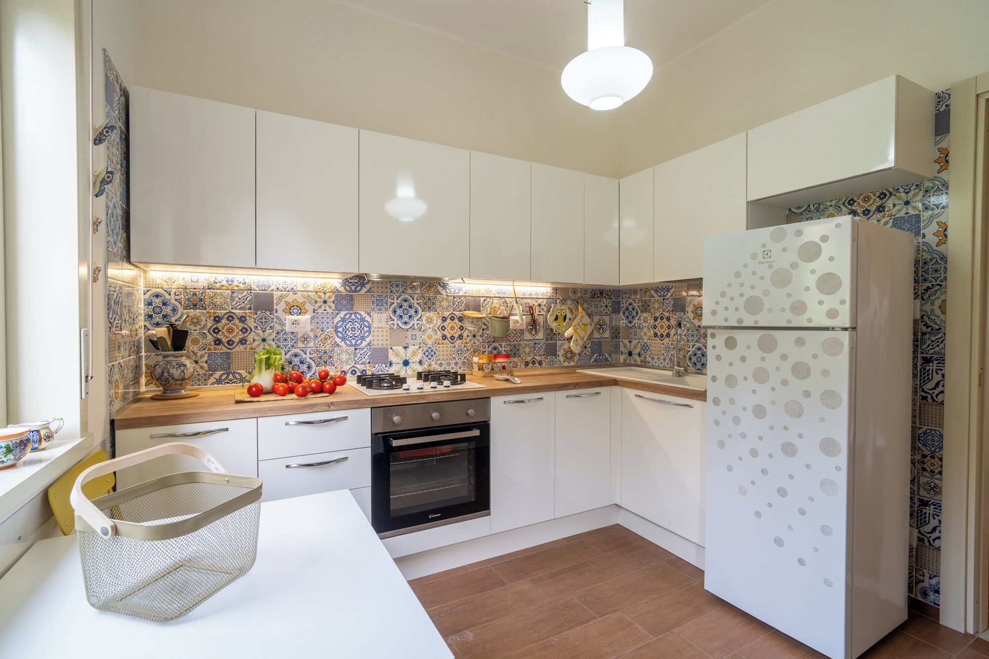 Una cocina moderna con armarios blancos, horno empotrado y salpicadero decorado.