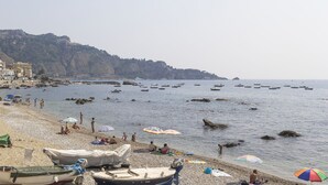 Una playa con barcos, sombrillas y gente.