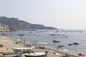 Ein Strand mit Booten, Sonnenschirmen und Menschen.