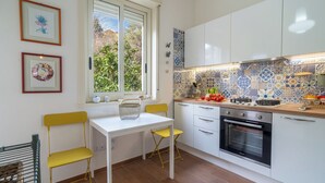 Una cocina moderna con armarios blancos, salpicadero de azulejos y una ventana con vista a follaje.