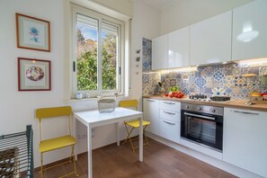 Eine moderne Küche mit weißen Schränken, einer Fliesenküchenwand und einem Fenster mit Blick ins Grüne.