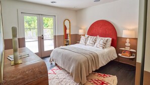 A bedroom with a bed, a nightstand, a mirror, and a door leading to an outdoor area. - Amazing 5 bdrms, 4 bath, private lake house, + guest house, 20 min from Atlanta (Fayetteville)