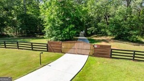 A gated pathway leading to a building with a paved entrance. - Amazing 5 bdrms, 4 bath, private lake house, + guest house, 20 min from Atlanta (Fayetteville)