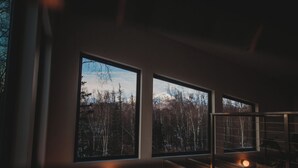 Ein Zimmer mit großen Fenstern mit Blick auf ein bewaldetes Gebiet.